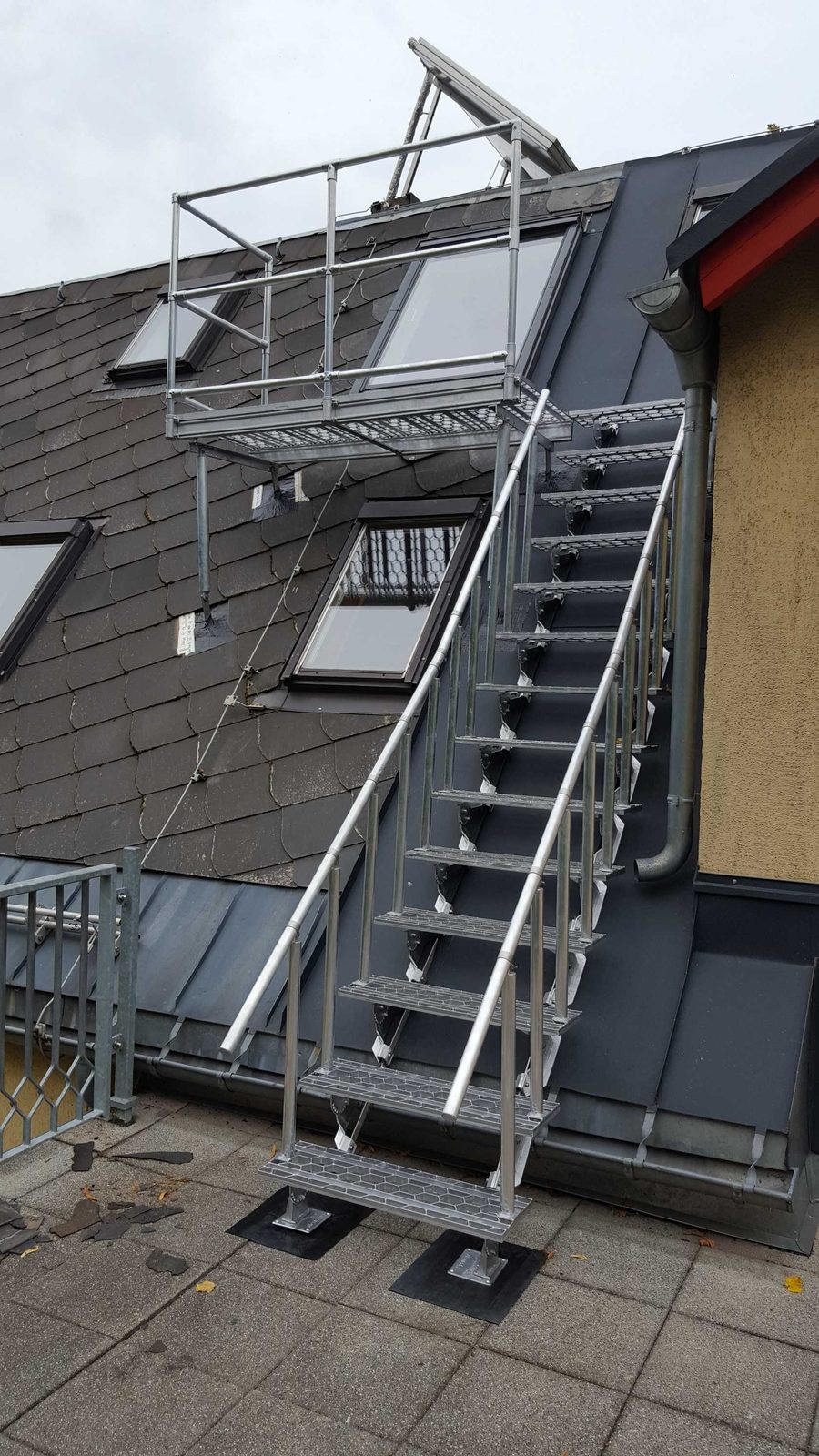 Stahltreppe mit Podest am Schieferdach, sie führt zu den Dachflächenfenstern